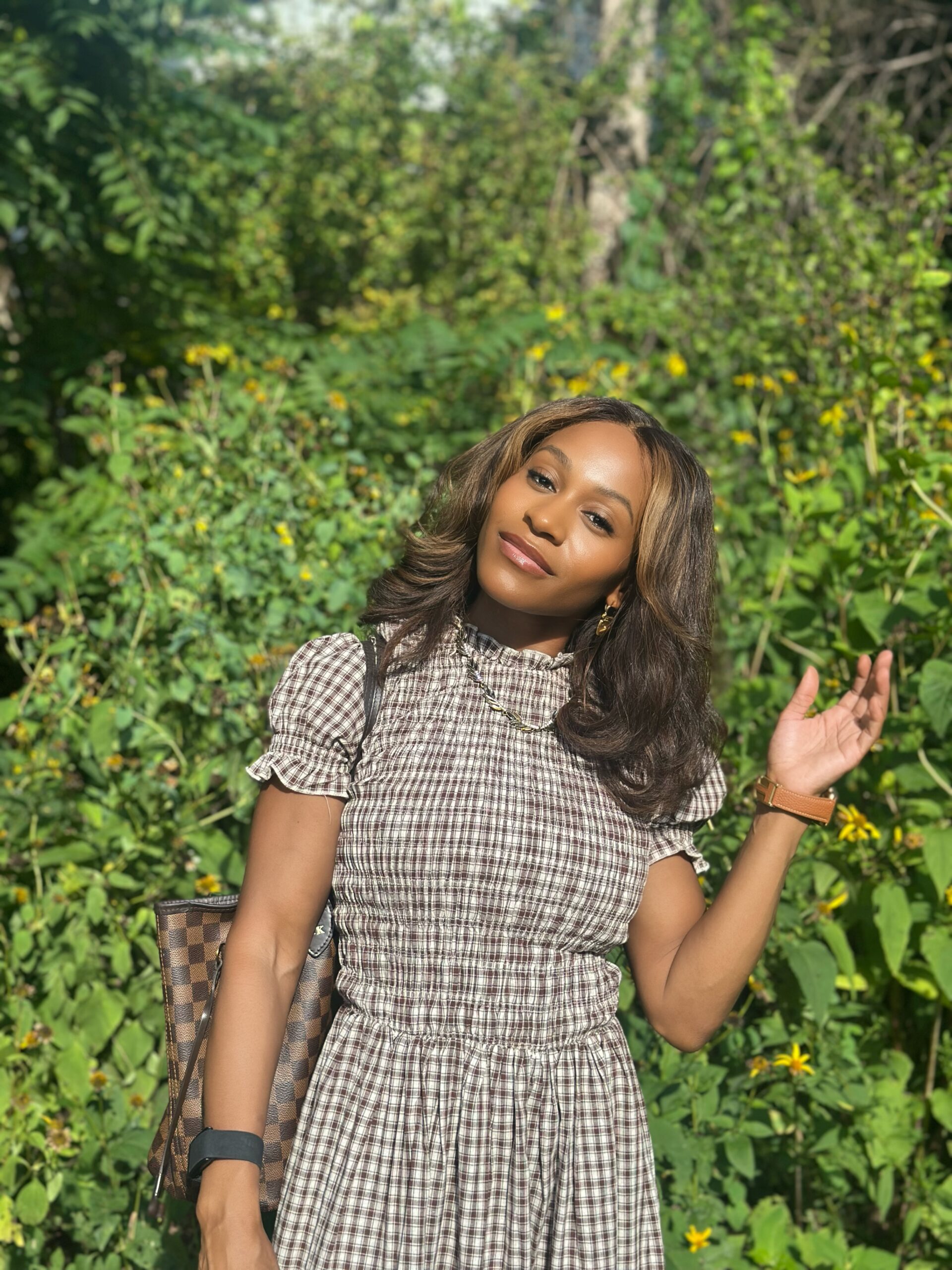 Brittany Kelly smiling outdoors in a brown-and-white checkered dress